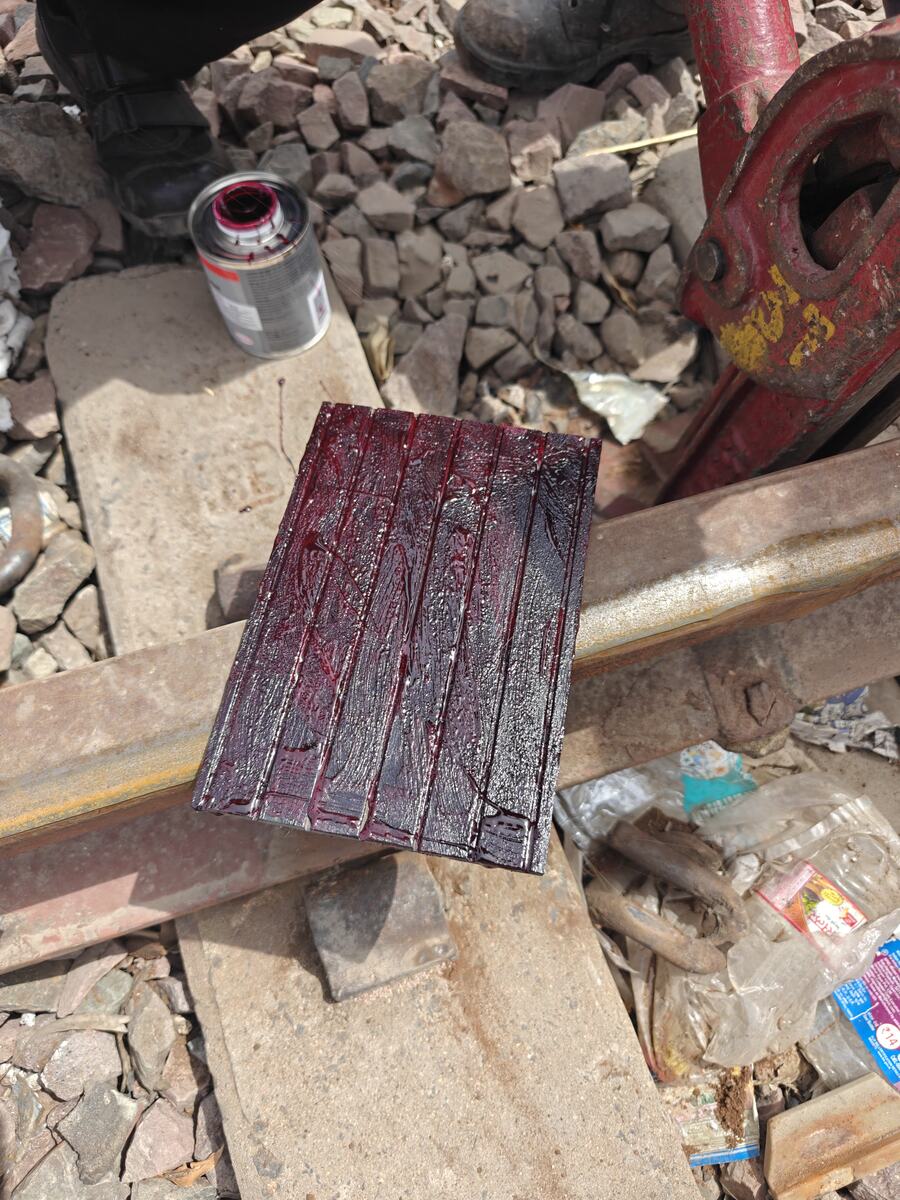 Adhesive freshly applied to a grooved rubber track pad at the trackside