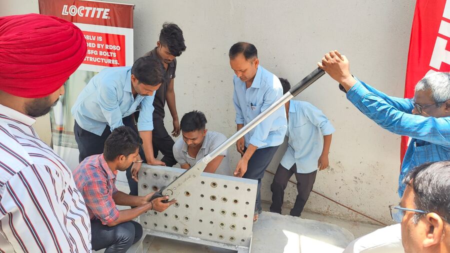 Torque wrench demonstration on a drilled HSFG splice assembly beside a LOCTITE banner