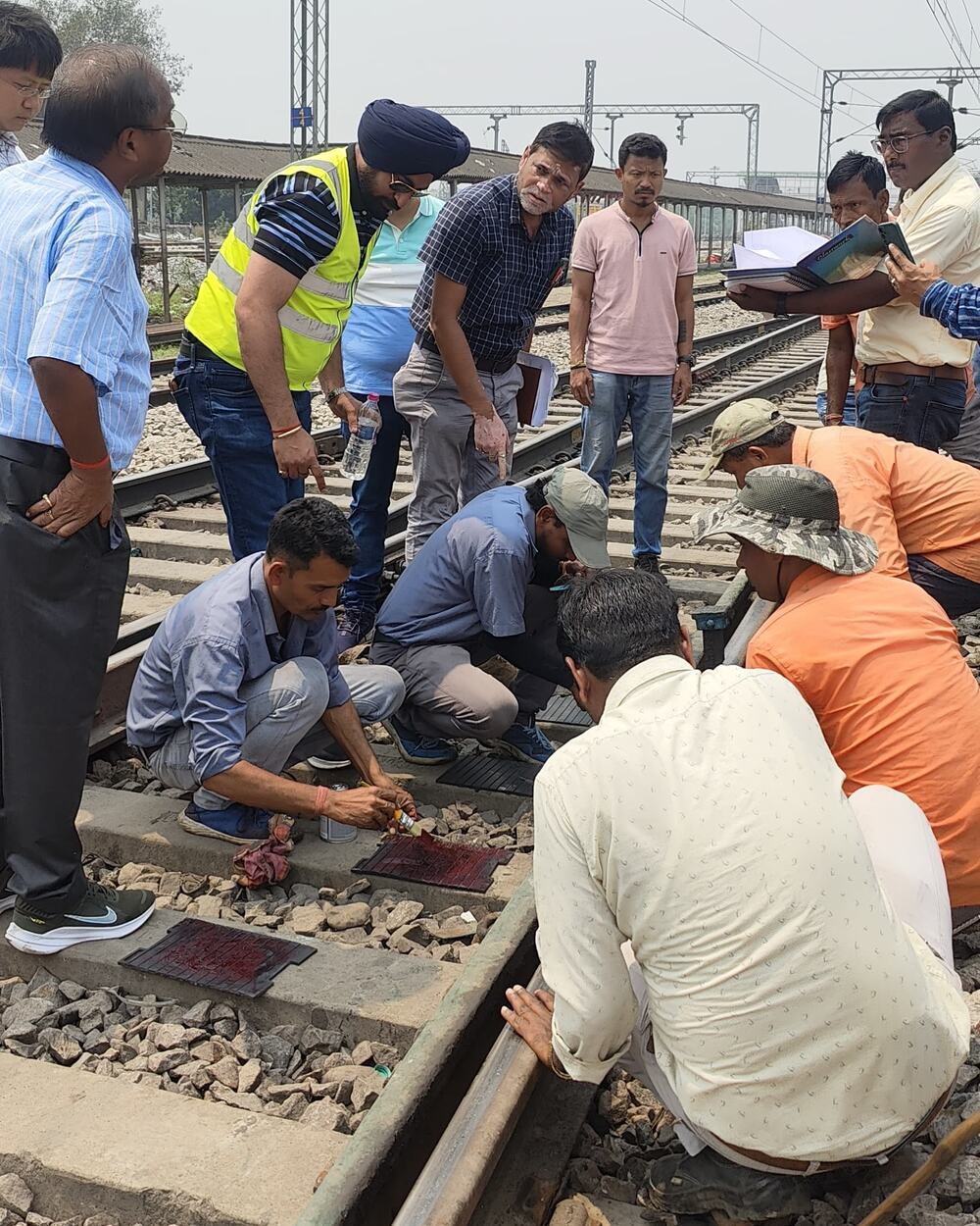 Bonding-agent application on track fittings with Railway officials observing