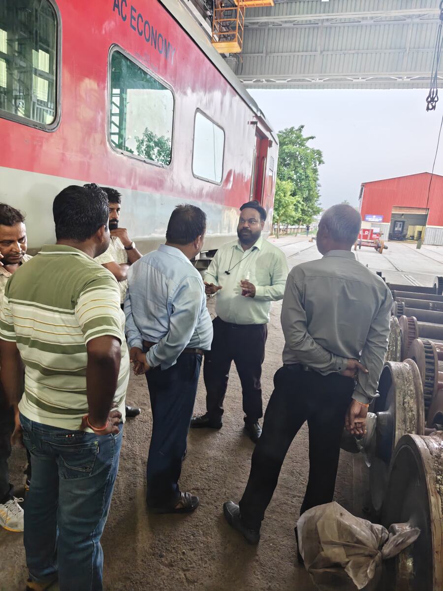Technical briefing beside an AC Economy coach in a Railway workshop